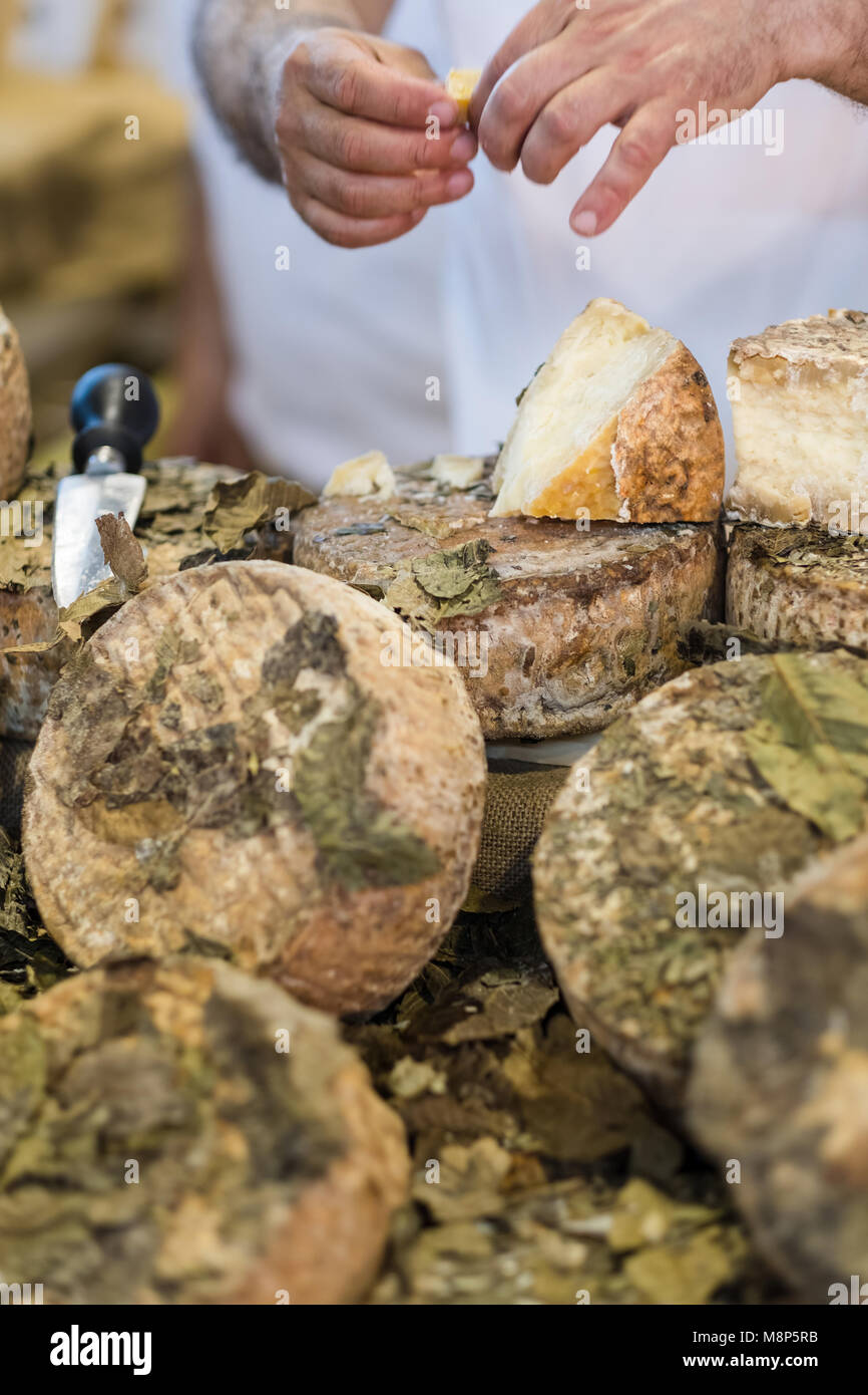 Lokale deli Arbeiter schneiden und mit Käse aus großen Käse Laibe Stockfoto