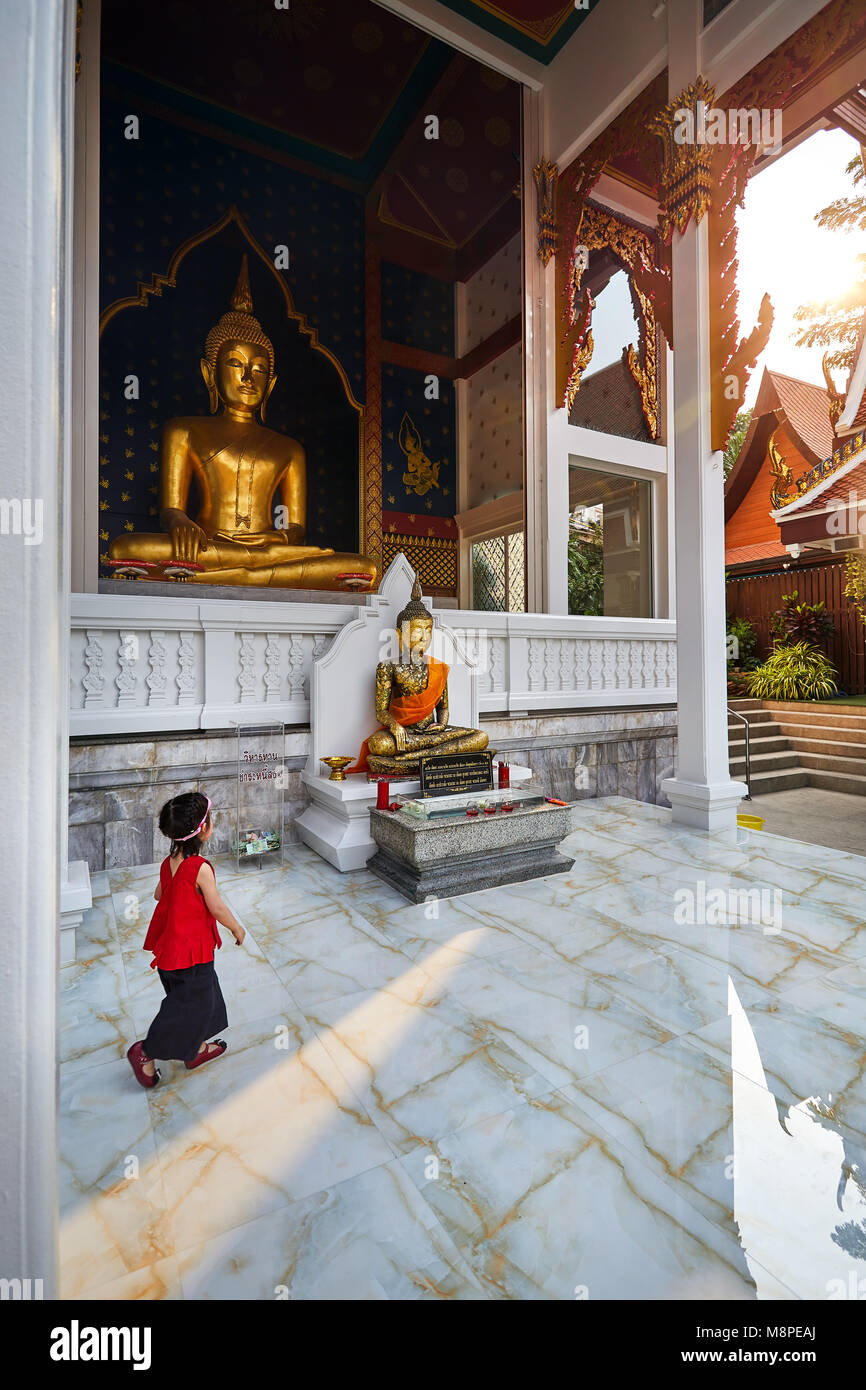 Kleine Mädchen zu Fuß in der Nähe von Golden Buddha Statue im Wat Saket bei Sonnenuntergang in Bangkok, Thailand Stockfoto