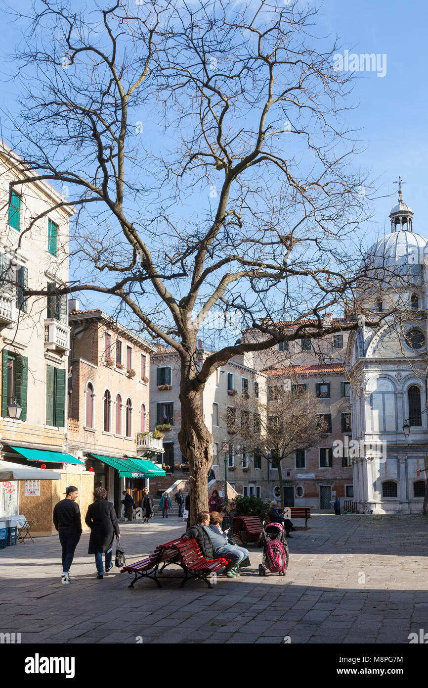 Campo Santa Maria Nova, Cannaregio, Venice, Veneto, Italien im Winter mit Menschen sitzen genießen die Nachmittagssonne und Chiesa di Santa Maria dei Miracoli Stockfoto