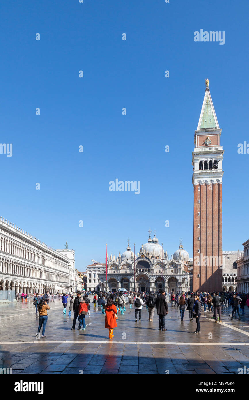 Touristen in St. Marks Platz, Piazza San Marco, nach acqua alta mit vielen tragen bunte Plastik über Schuhe, Venedig, Venetien, Italien auf einem sonnigen ble s Stockfoto