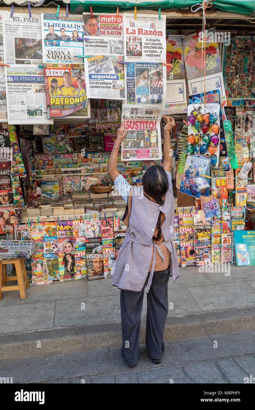 Oaxaca Oax., Mexiko - ein Kiosk Betreiber fügt eine Zeitung, die Sie verkaufen. Stockfoto