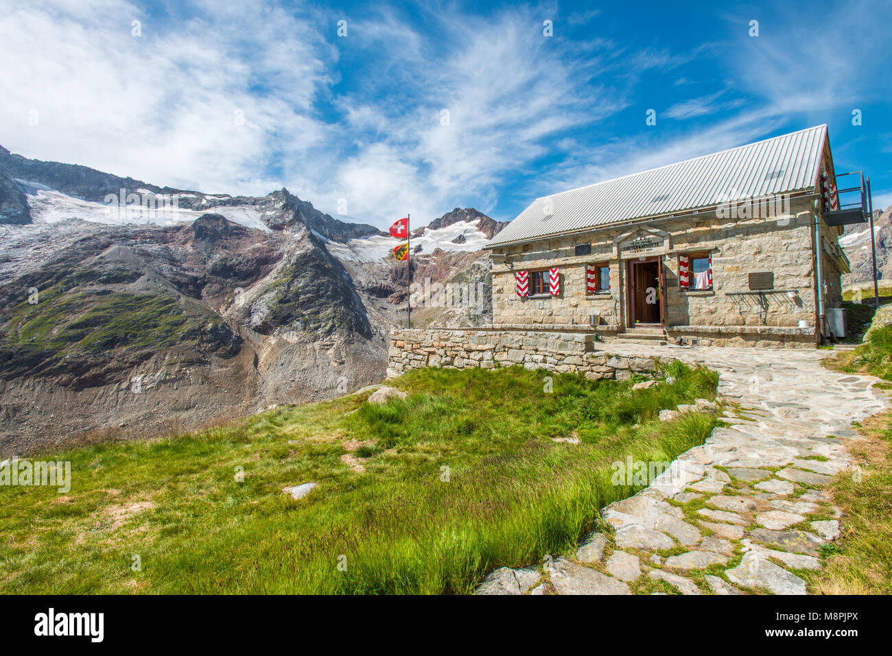 Schweizer Berghütte, Almhütte am Ende des Weges zu Grimsel Gletscher. Beeindruckende Bergwelt umhüllt das Tal. Stockfoto