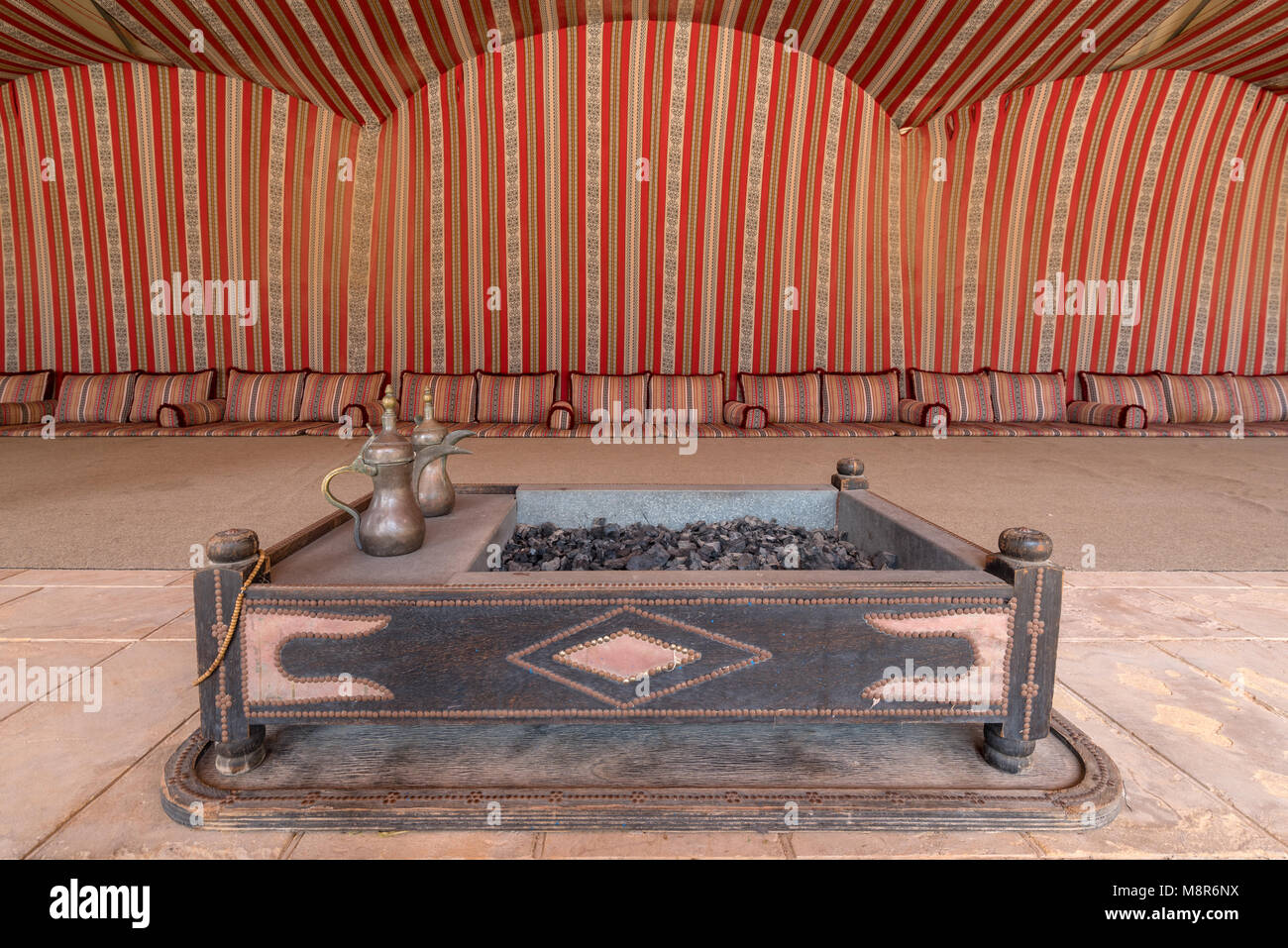 Das Innere eines großen traditionellen arabischen Zelt mit rot gemusterten Gewebe gefüttert und den Boden in die Kissen fallen zu sitzen Stockfoto