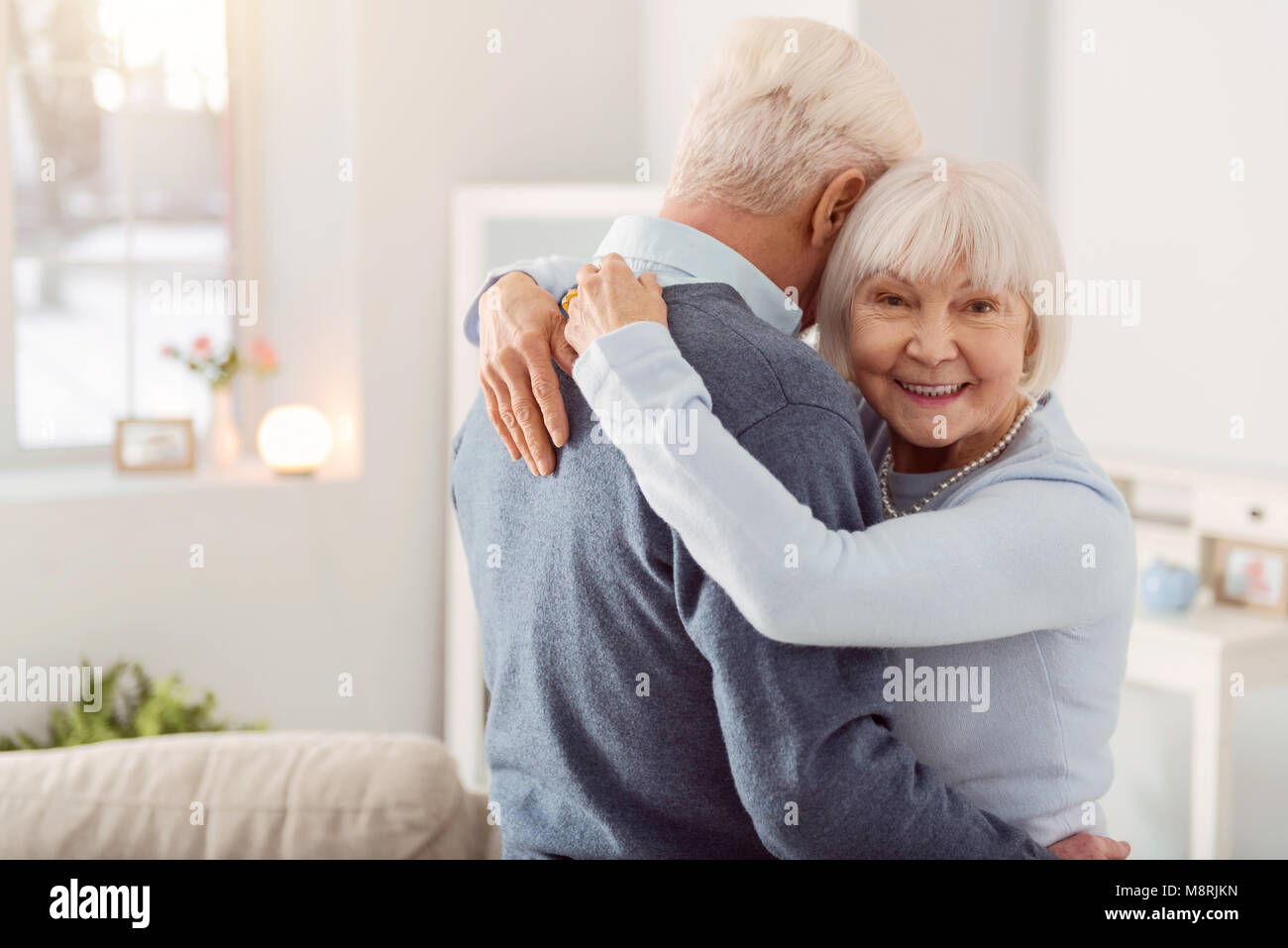 Freundliche ältere Frau posiert während ihr Mann umarmen Stockfoto