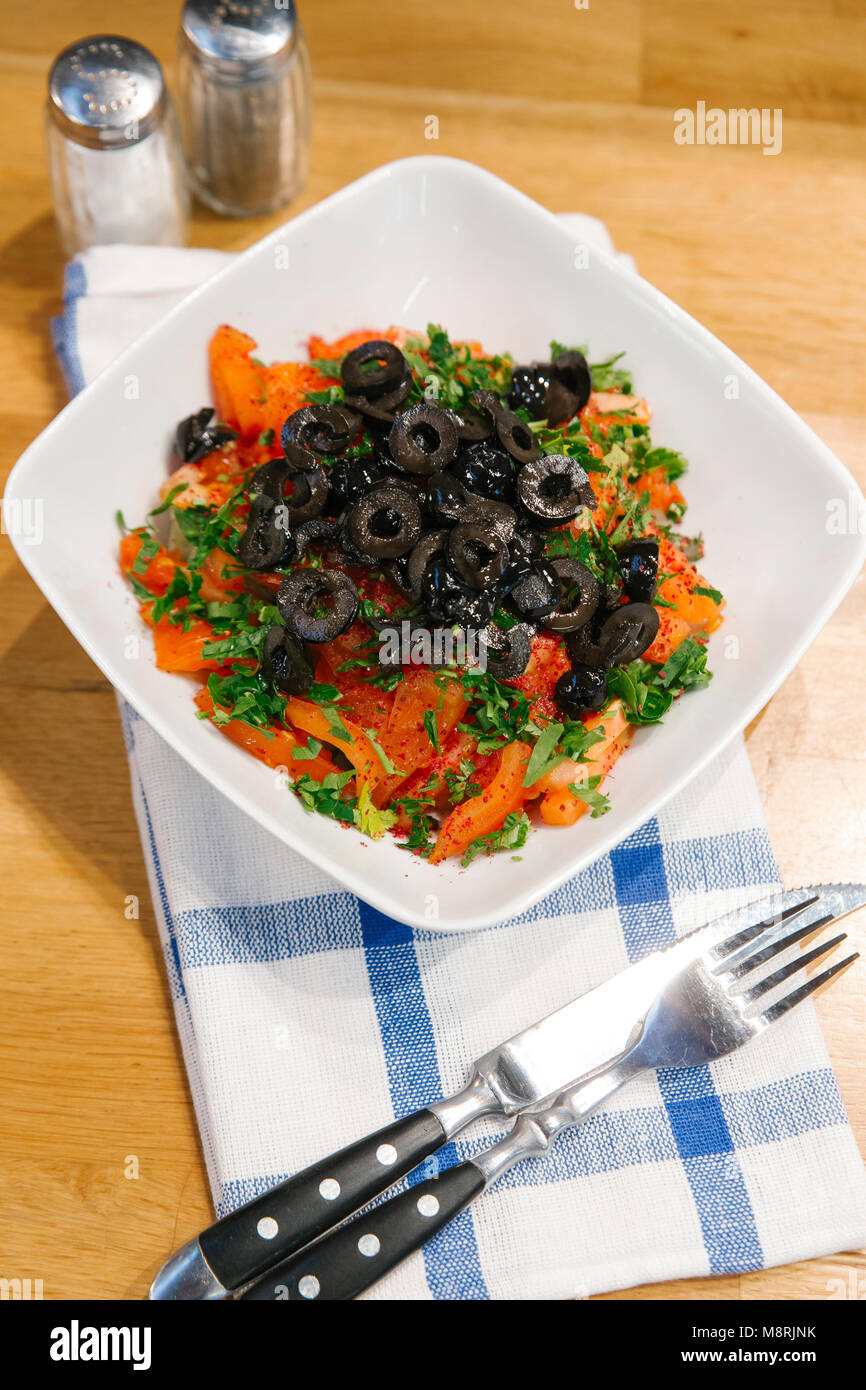 Hohe Betrachtungswinkel von Tomaten Salat in der Schüssel mit Besteck und Serviette auf hölzernen Tisch Stockfoto