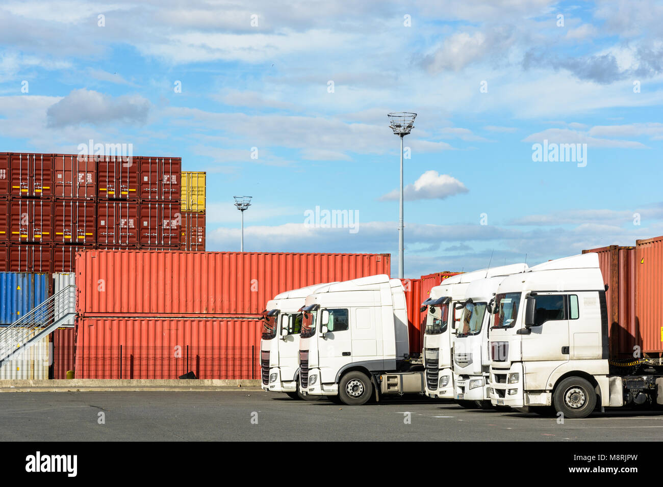 Eine Reihe von weißen semi-trailer Trucks auf den Container Storage Plattform der intermodalen Terminal eines Flusses Hafen mit Containern geparkt in der backgrou Stockfoto