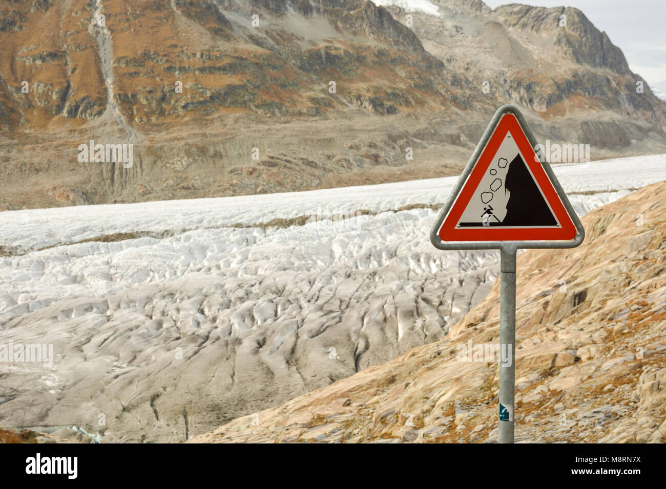 Schild mit Warnung vor herabfallenden Felsen in der Nähe von Aletsch Gletscher in den Schweizer Alpen Stockfoto