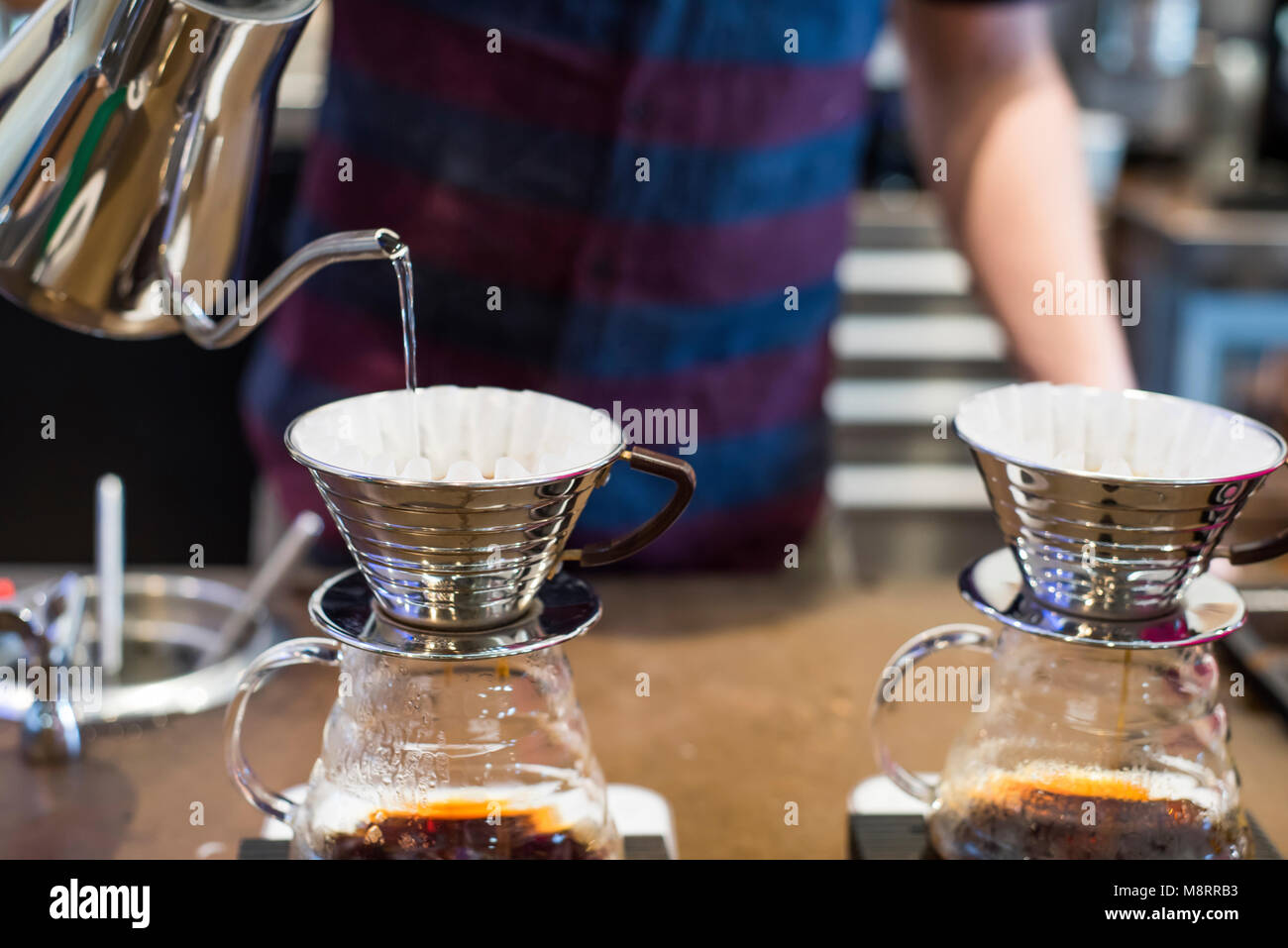 Barista gießt kochendes Wasser in Kaffee Filter im Cafe Stockfoto
