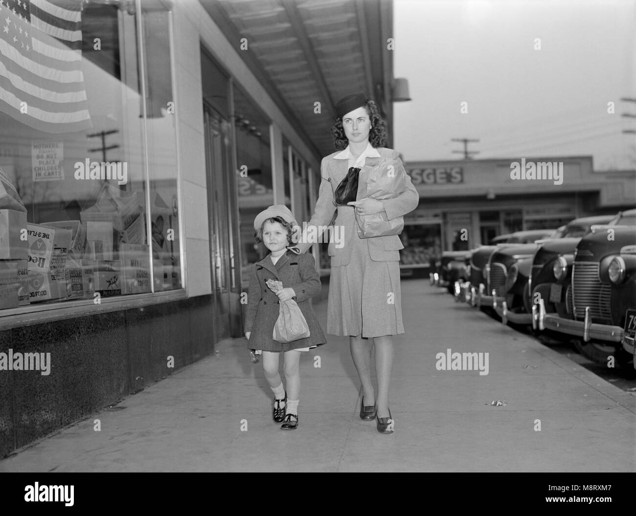 Mutter und Tochter nach Hause mit Bündeln nach dem Einkaufen beim Helfen zu sparen Reifen auf dem Auto oder Lkw des Händlers sowie, während des Krieges bemühen, Ann Rosener, Office of War Information, Februar 1942 Stockfoto