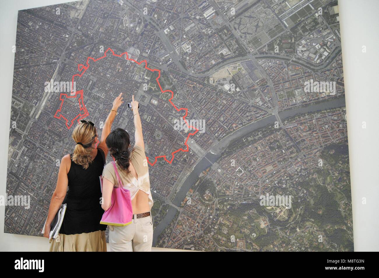 Zwei Frauen stehen vor riesigen reklametafeln Luftaufnahme der Stadt Erweiterung im Vergleich zu den alten Zeiten durch die Roten stratch Turin signalisiert Stockfoto