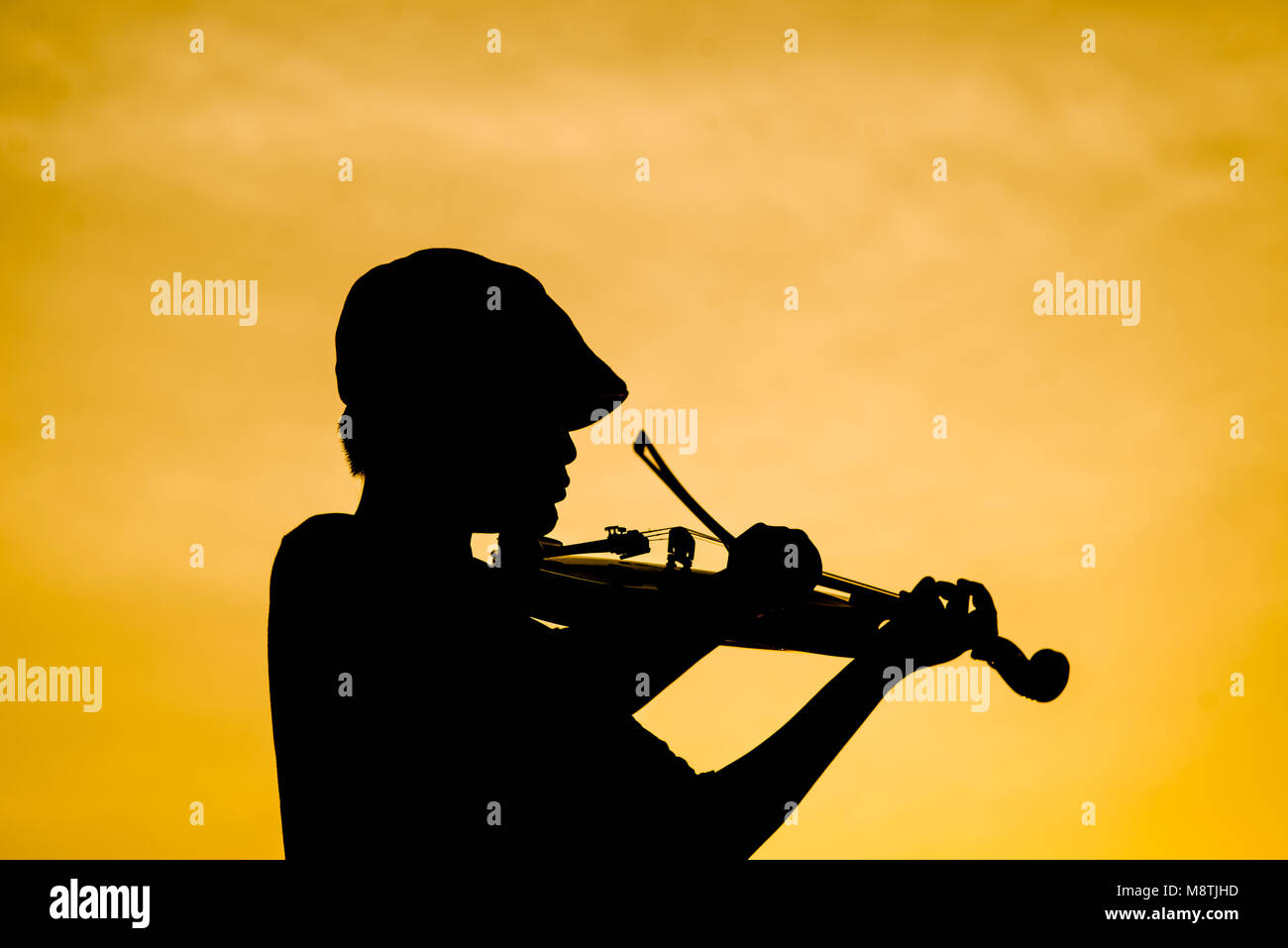 Silhouette Junge spielt Violine bei Sonnenuntergang. Stockfoto