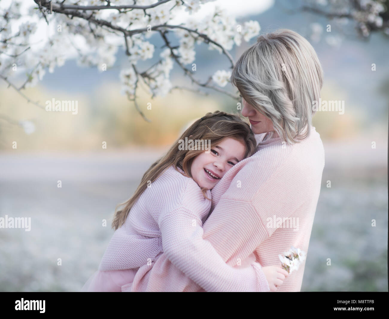 Familie Liebe und Lifestyle. Portrait von Mutter und Tochter sanft im Garten Umarmung mit blühenden Almendra Stockfoto