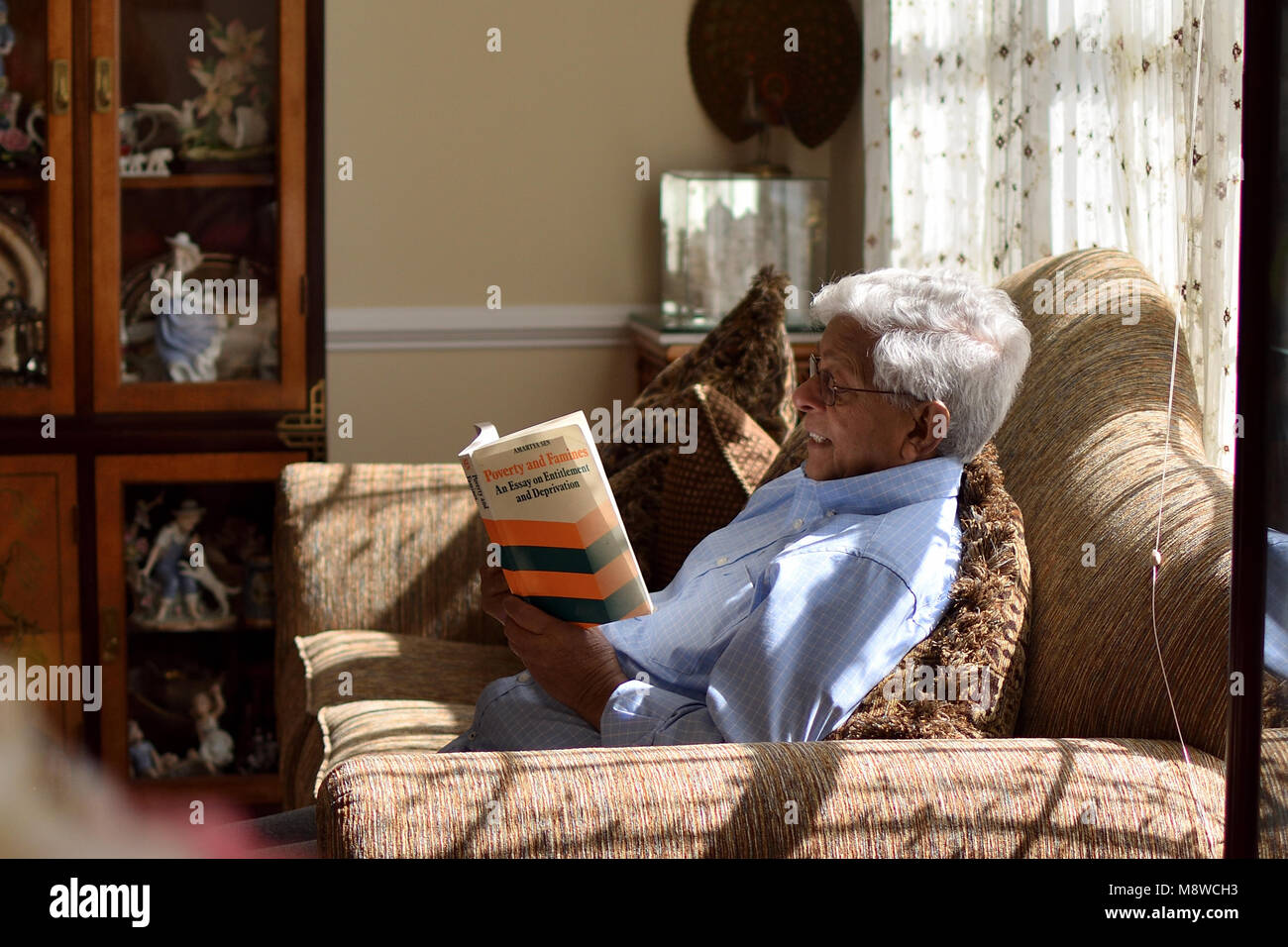 Genießen "Armut und Hungersnöte: ein Essay über den Anspruch und Entbehrungen" von Nobelpreisträger Dr. Amartya Sen, auf einen entspannten Sonntag Nachmittag. Stockfoto