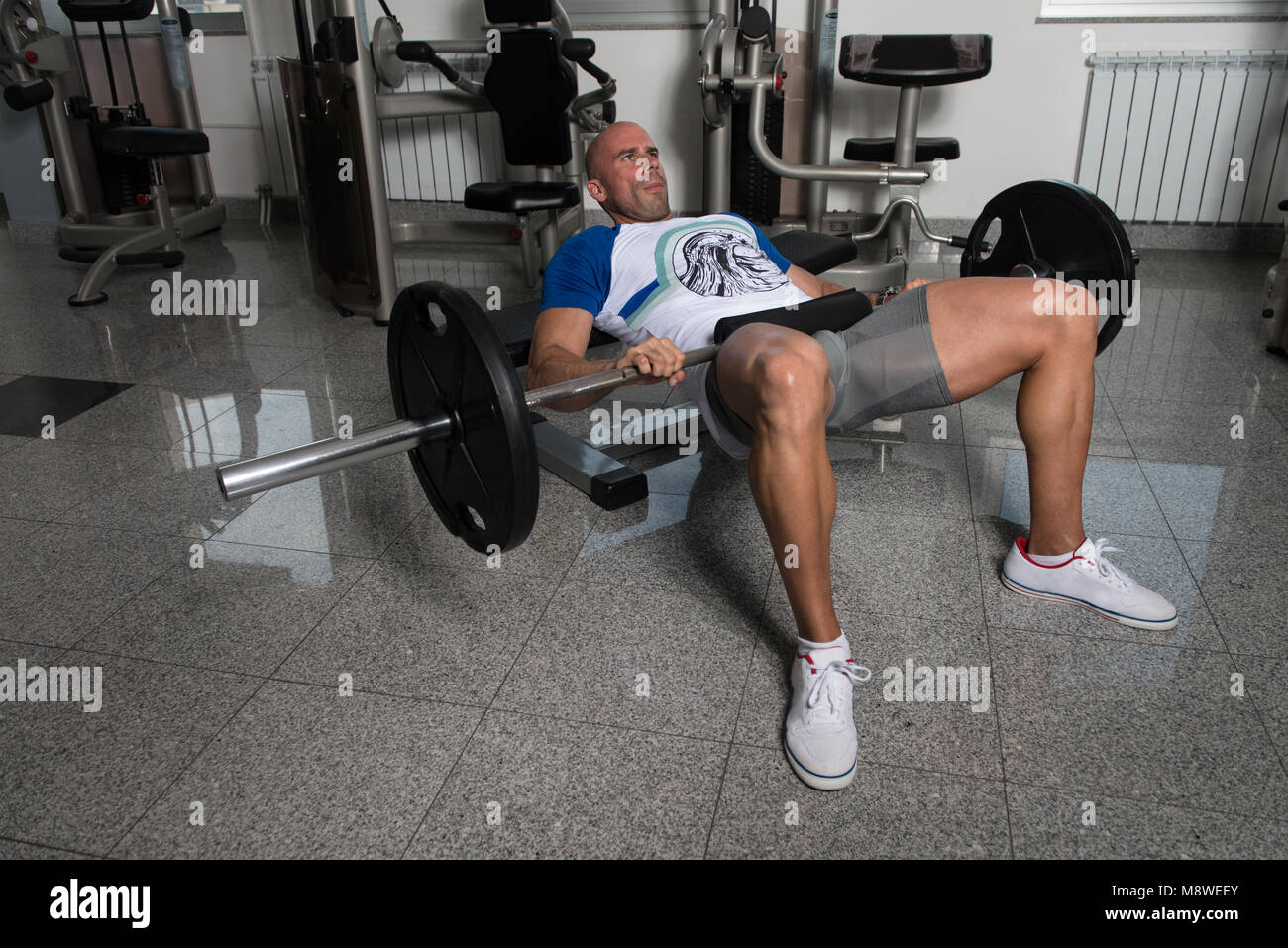 Starker Mann In der Turnhalle trainieren Beine mit Langhantel - Muskulös athletisch Bodybuilder Fitness Modell Übung Stockfoto