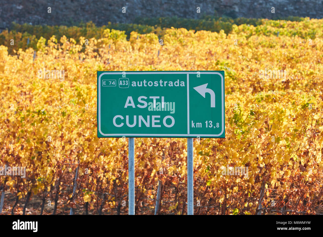 Asti Cuneo Autobahn Straßenschild und Weinberg im Herbst mit gelben Blätter an einem sonnigen Tag in Italien Stockfoto