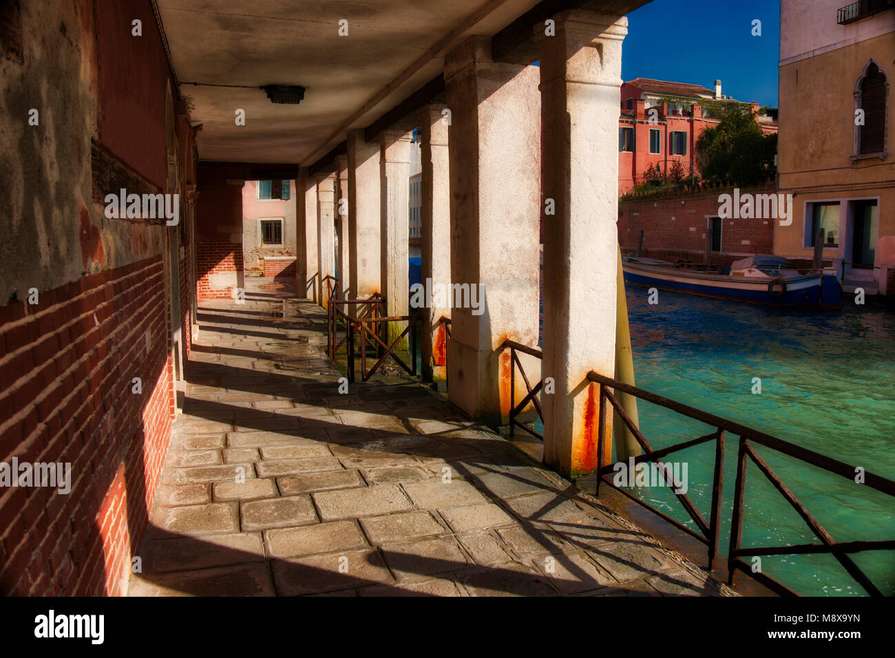 Ein sonniger Gehweg an der Seite von einem Kanal in Venedig, Italien. Stockfoto