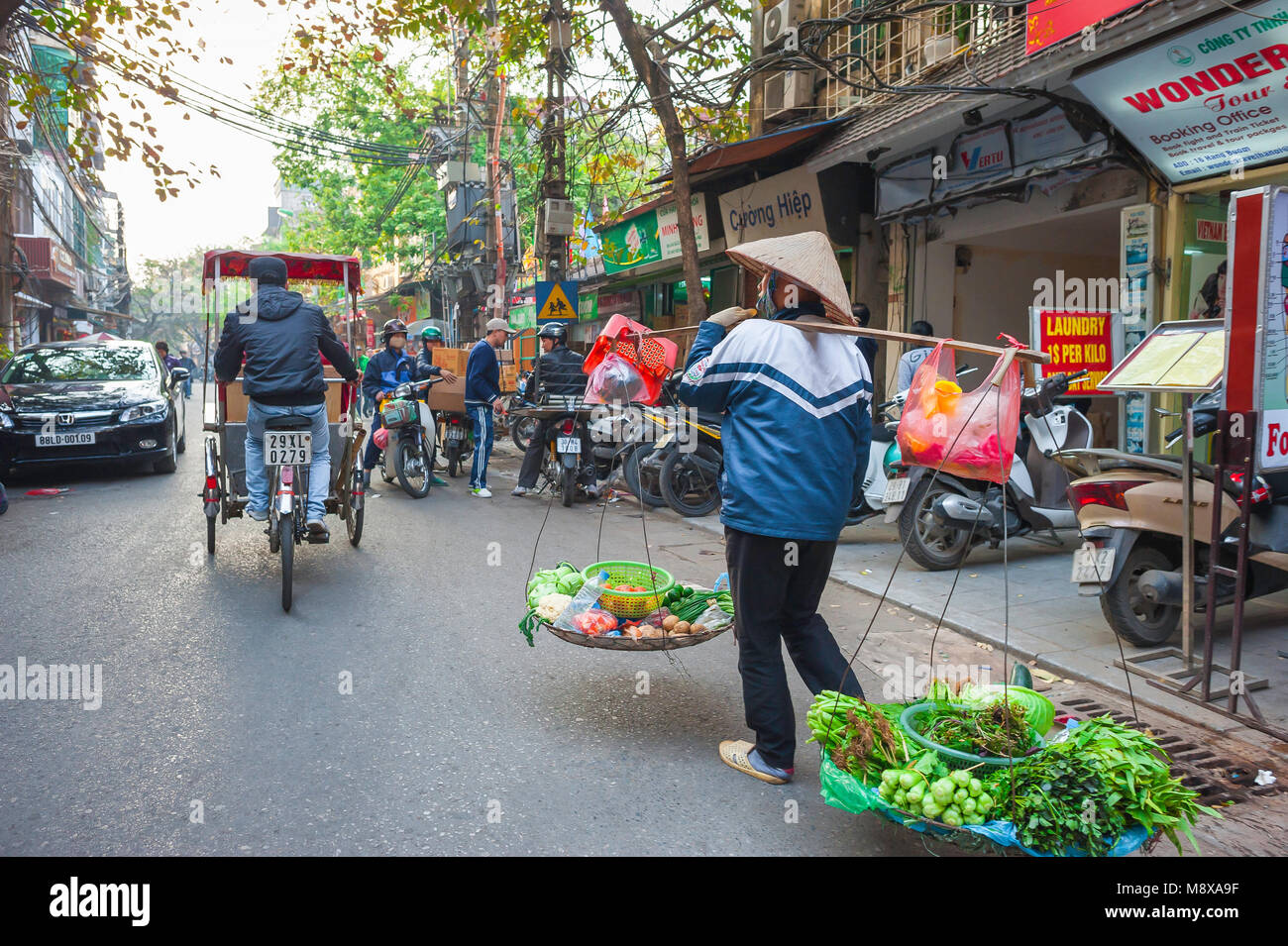 Hanoi Old Quarter, eine weibliche Verkäufer Gemüse Transporte durch die Straßen der historischen Altstadt im Zentrum von Hanoi, Vietnam. Stockfoto