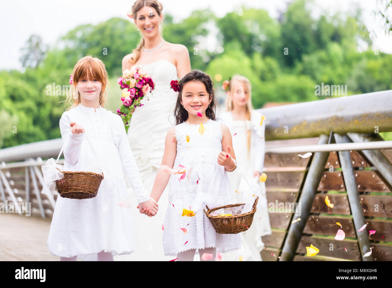 Braut im Brautkleid mit brautjungfern auf Brücke Stockfoto