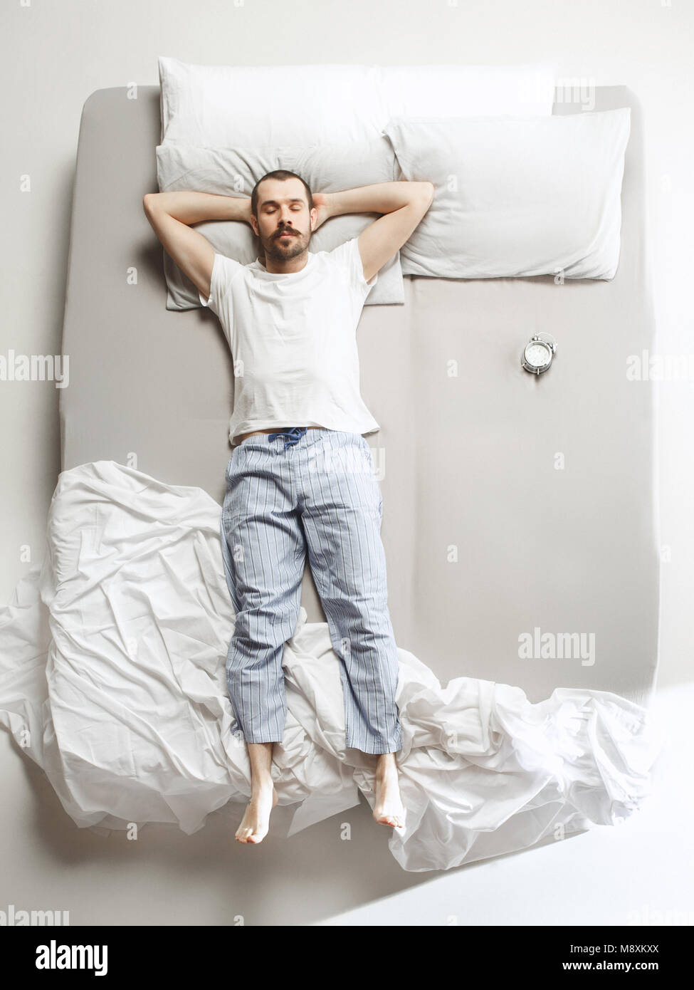 Ansicht von oben Foto des jungen Mannes schlafen in einem großen weißen Bett Stockfoto