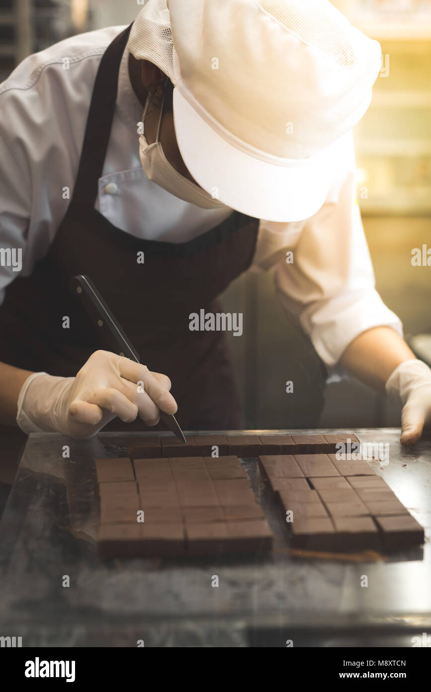 Koch schneiden hausgemachte Schokolade in der Küche. Stockfoto