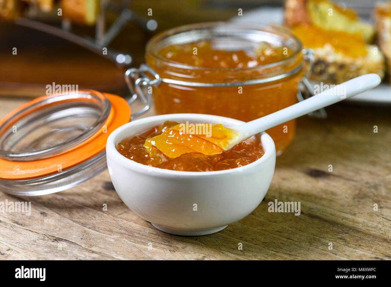 Frühstück mit hausgemachten Bio Marmelade in einer kleinen weißen Schale mit größeren Betrag in einem Einmachglas auf einer alten Küche aus Holz Tisch c Stockfoto