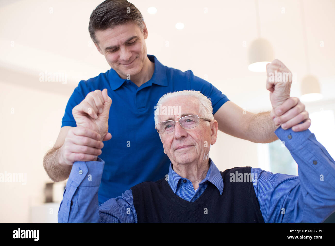 Männliche Krankenschwester Bewertung Senior Schlaganfall Opfer durch Anheben der Arme Stockfoto