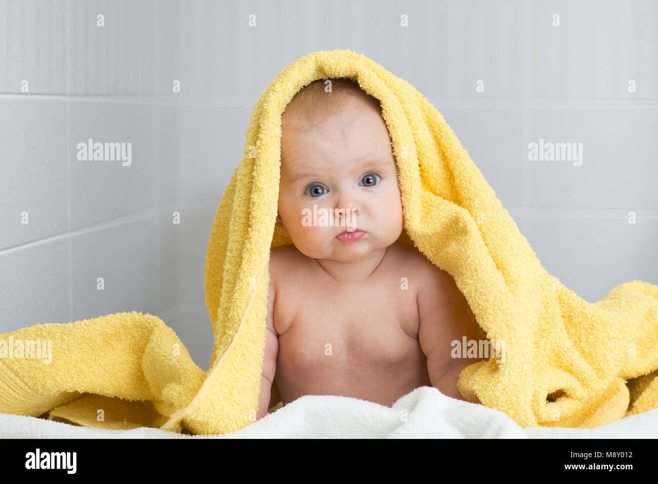 Cute Baby in gelben Badetuch im Badezimmer Stockfoto
