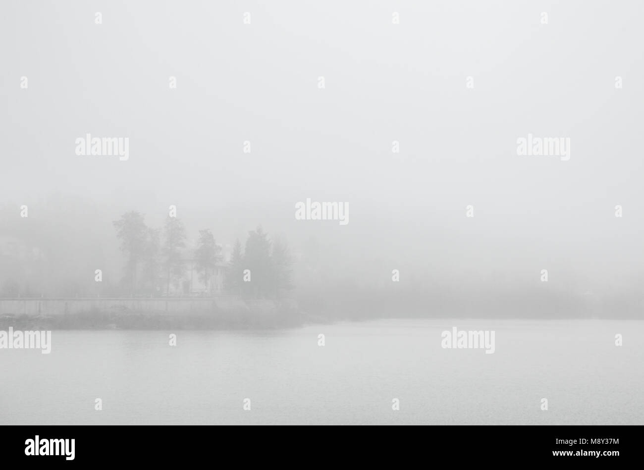 Dichter Nebel umgibt ein Haus auf der anderen Seite des Sees Matese in Kampanien, Italien. Stockfoto