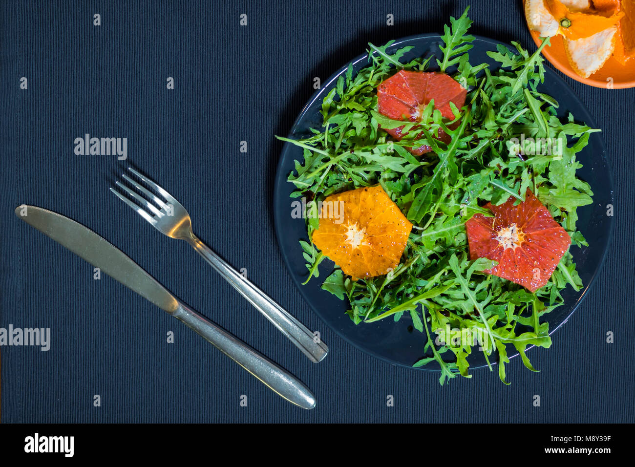 Grüner Salat aus Rucola auf einem Teller mit Scheiben von Orange und Grapefruit Stockfoto