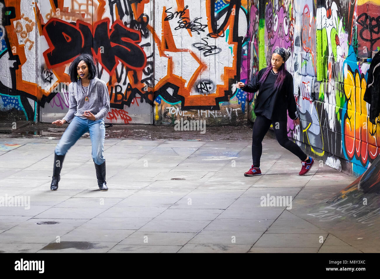 Zwei junge Mädchen üben ein Tanz auf der Eingabeseite für die South Bank Undercroft Skate Park in London. Stockfoto