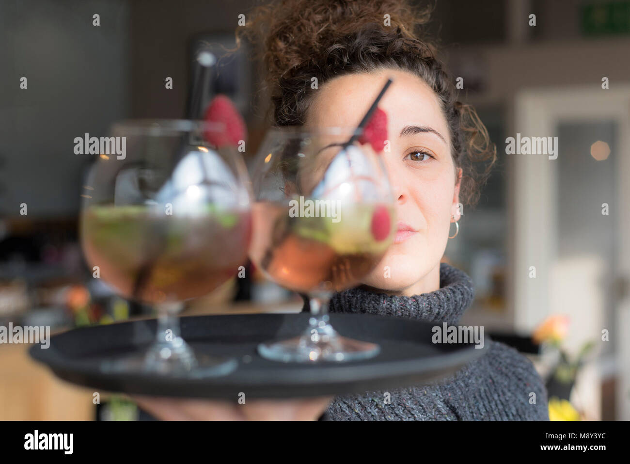 Eine Kellnerin mit einem Tablett mit Cocktails. Stockfoto