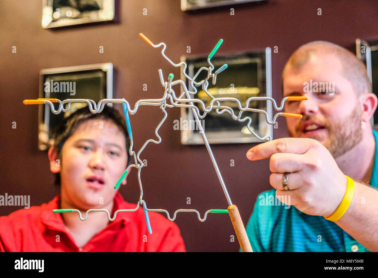 Ein autistischer Junge spielt Magnetische balancing Sticks mit einem Berater an einem Spiel Zimmer Stockfoto