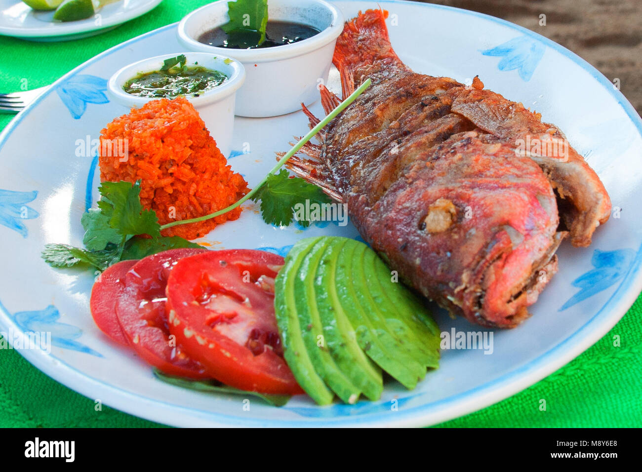 Frittierte Red Snapper mit Avocado- und Tomatenscheiben zusammen mit ...