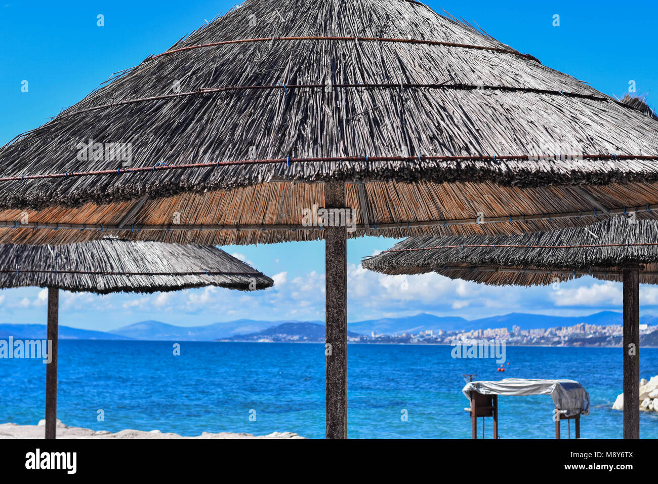 Schirm und ein Bambus Sonnenschutz in einem leeren Paradise Beach an einem  sonnigen Tag Stockfotografie - Alamy
