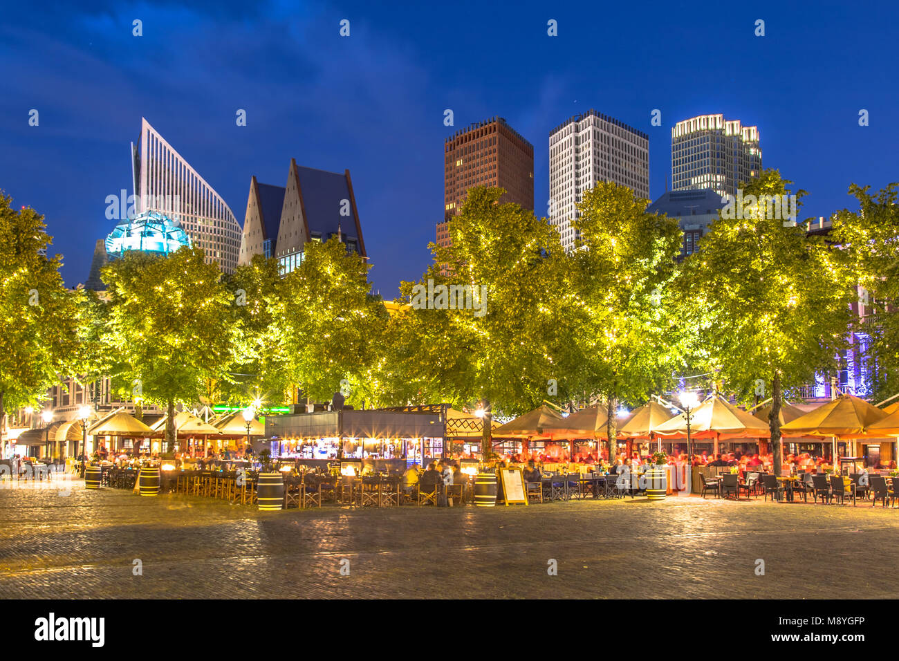 Berühmte Plein square Den Haag in der Nacht. Die Leute trinken auf teracces mit staatlichen Ministerium skyscraper Büros in den Hintergrund. Stockfoto