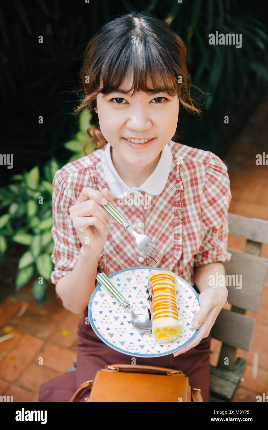 Asiatische Mädchen Jugendliche hipster Glückliches essen Dessert kuchen Roll Stockfoto