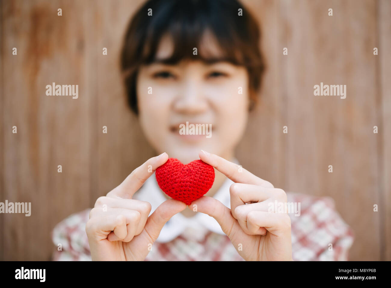 Nette junge Asien Frau, die roten Herzen auf Holz- hintergrund Vintage colortone Stockfoto