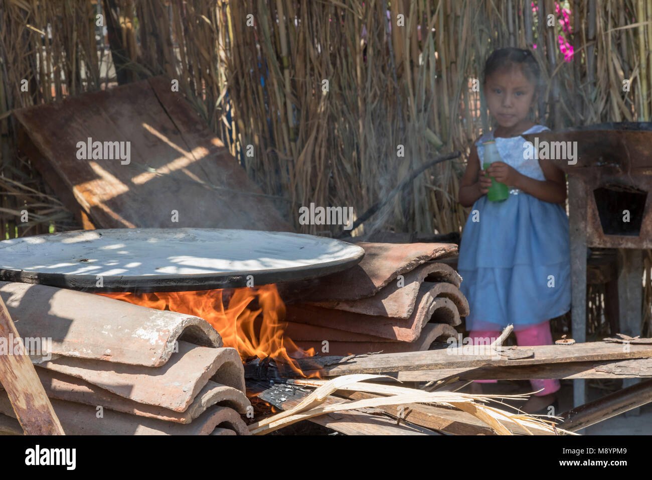 San Juan Teitipac, Oaxaca, Mexiko - ein Mädchen Uhren eine comal Heizung auf offenem Feuer während des sprachlichen und kulturellen Erbes Messe in einem kleinen Zapotec Stadt. Th Stockfoto