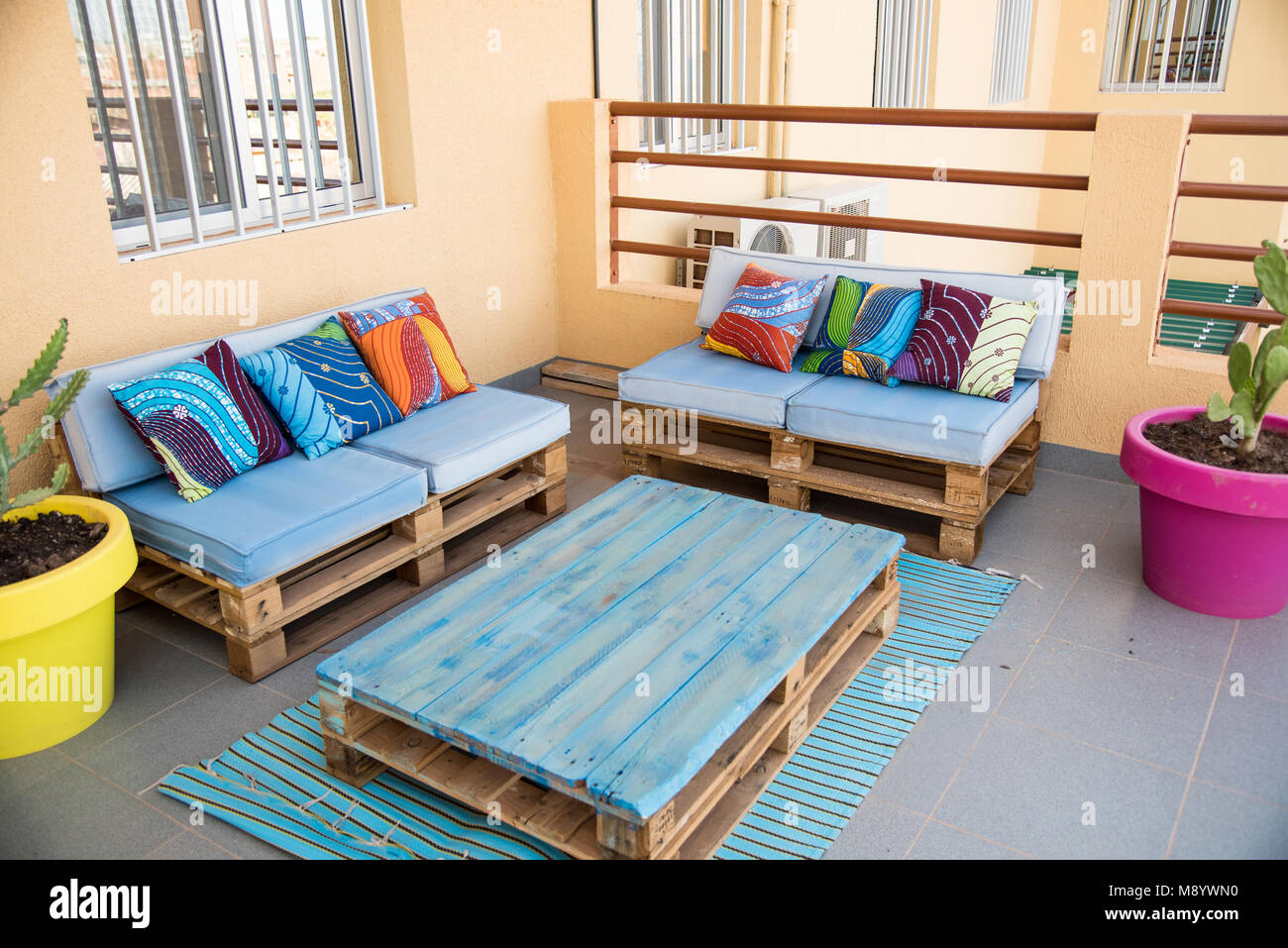 Cool Terrassenmöbel aus Holzpaletten. Blau lackiert mit kräftigen, bunten afrikanischen Stoff Kissen. Hell und glücklich. Stockfoto