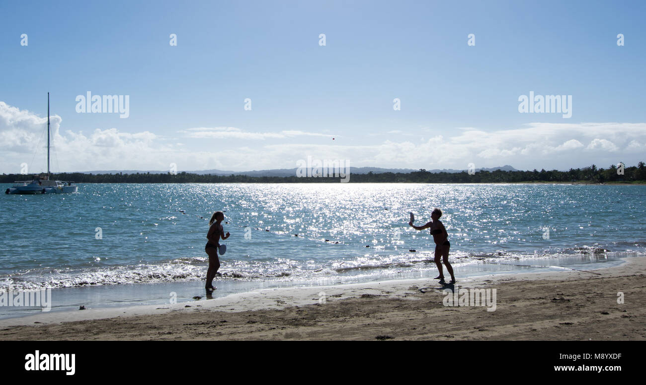 Paar Spiel mit Schläger und Ball gegen die suns glare Silhouette am Strand Stockfoto