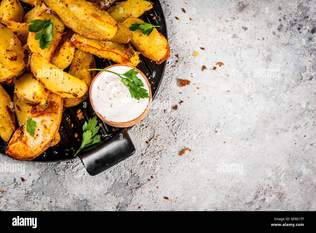 Gebackene Kartoffeln mit Knoblauch, Kräutern, roten und weißen Soßen, am grauen Stein Background Copy space Top View Stockfoto