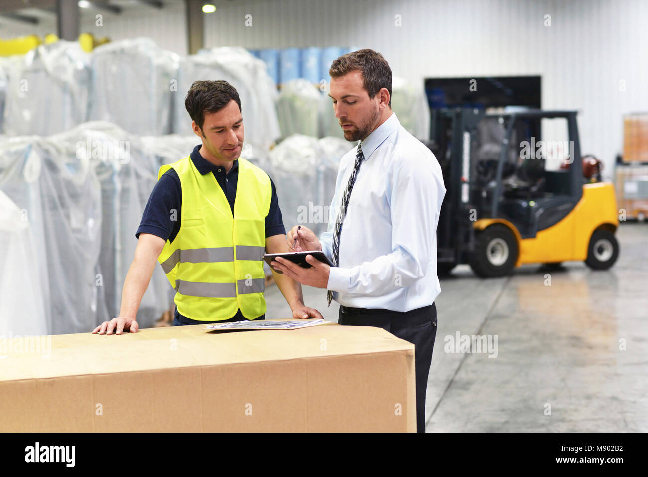 Treffen der Manager und Mitarbeiter im Lager - Gabelstapler und Innenraum der industriellen Gebäude Stockfoto