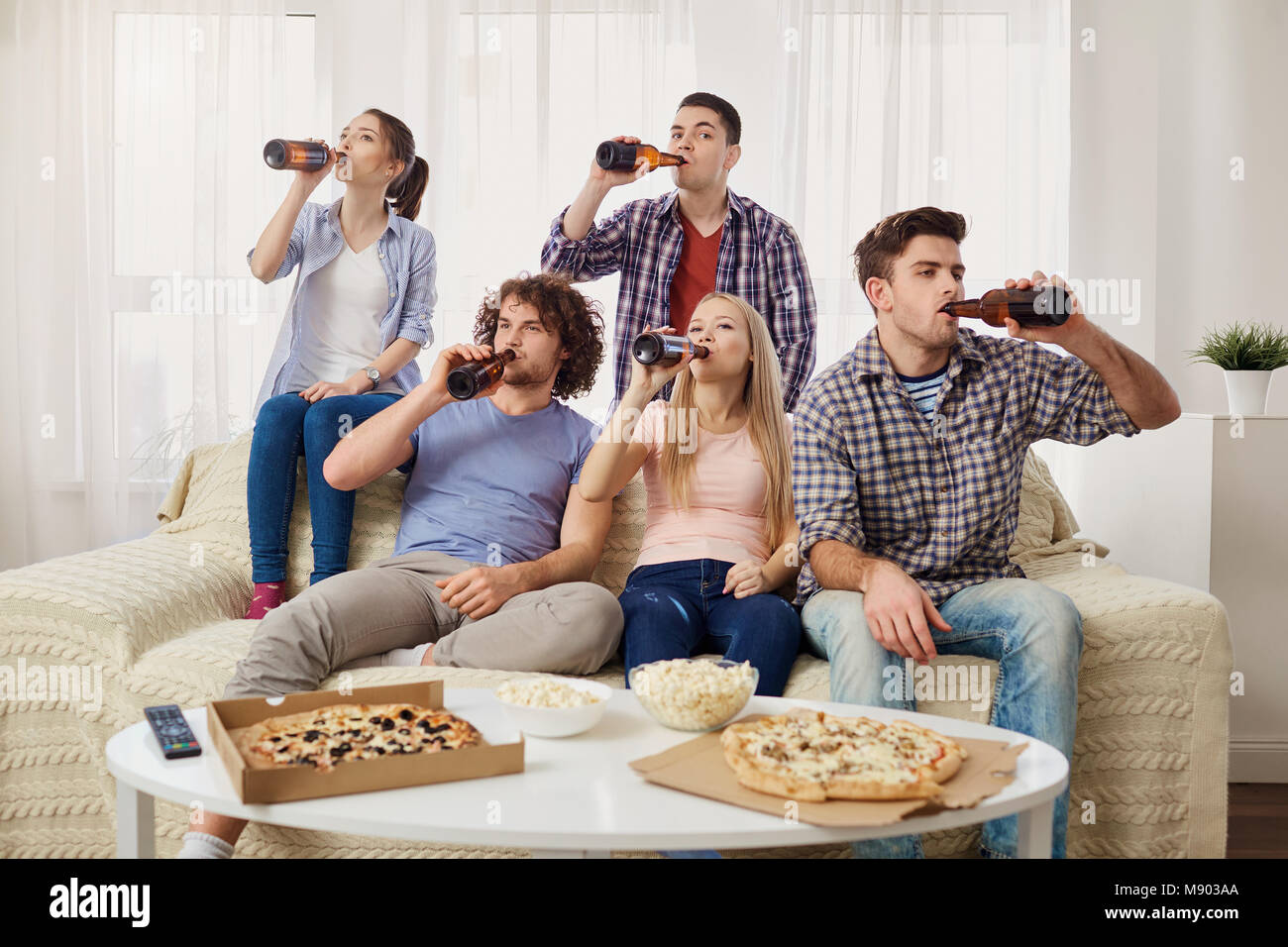 Eine Gruppe von Freunden trinken Bier aus der Flasche im Zimmer. Stockfoto