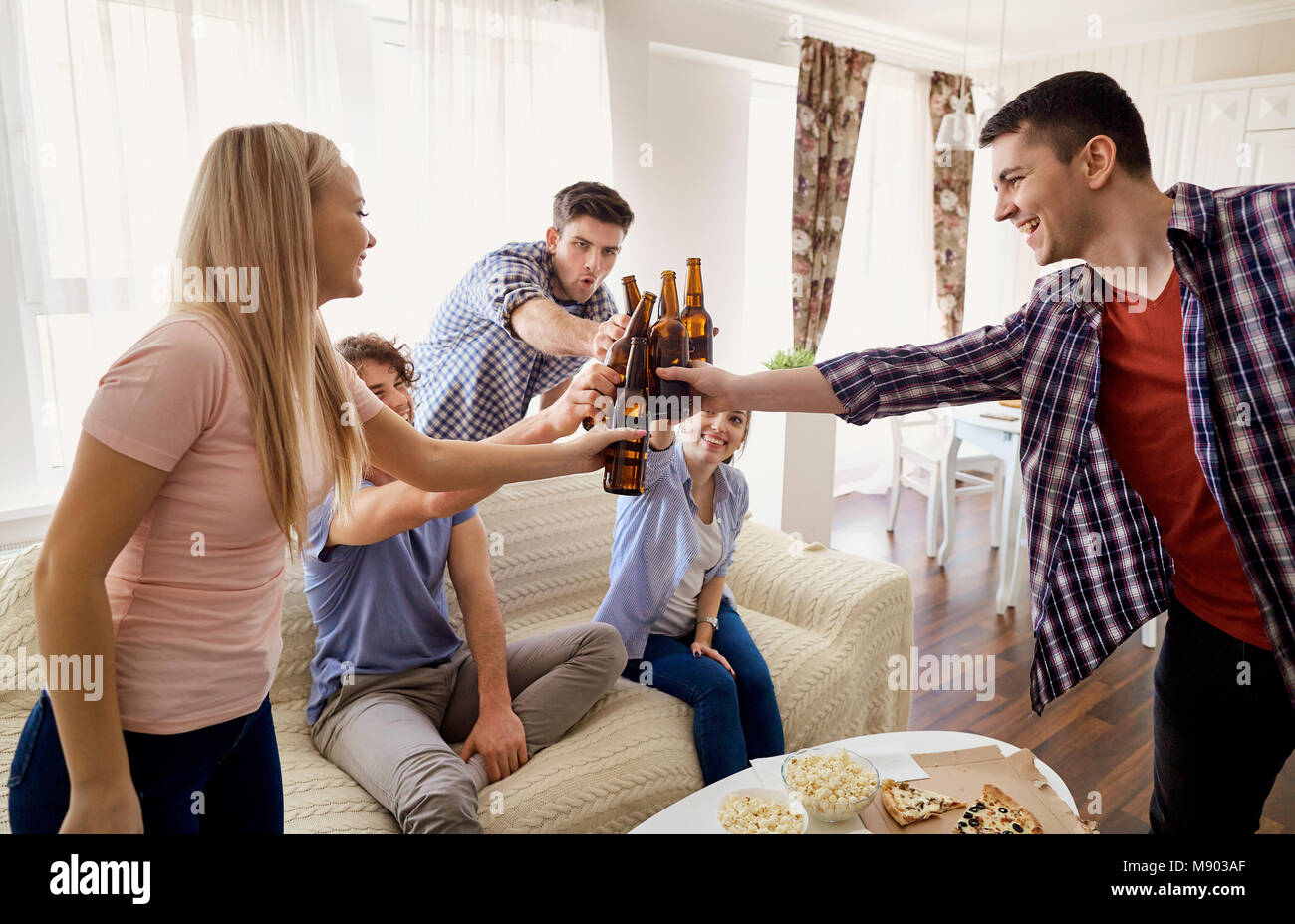 Eine Gruppe von Freunden sind, klirrenden Flaschen in einer Sitzung. Stockfoto