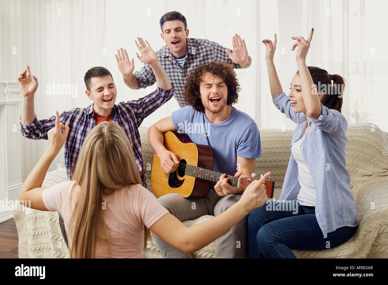 Eine Gruppe von Freunden mit einer Gitarre Songs auf einer Party innen Singen Stockfoto