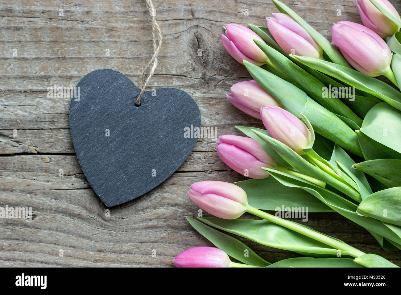 Ansicht von oben Schönen Blumenstrauß rosa und violett Tulpen mit einem Herzen aus Holz Hintergrund Stockfoto