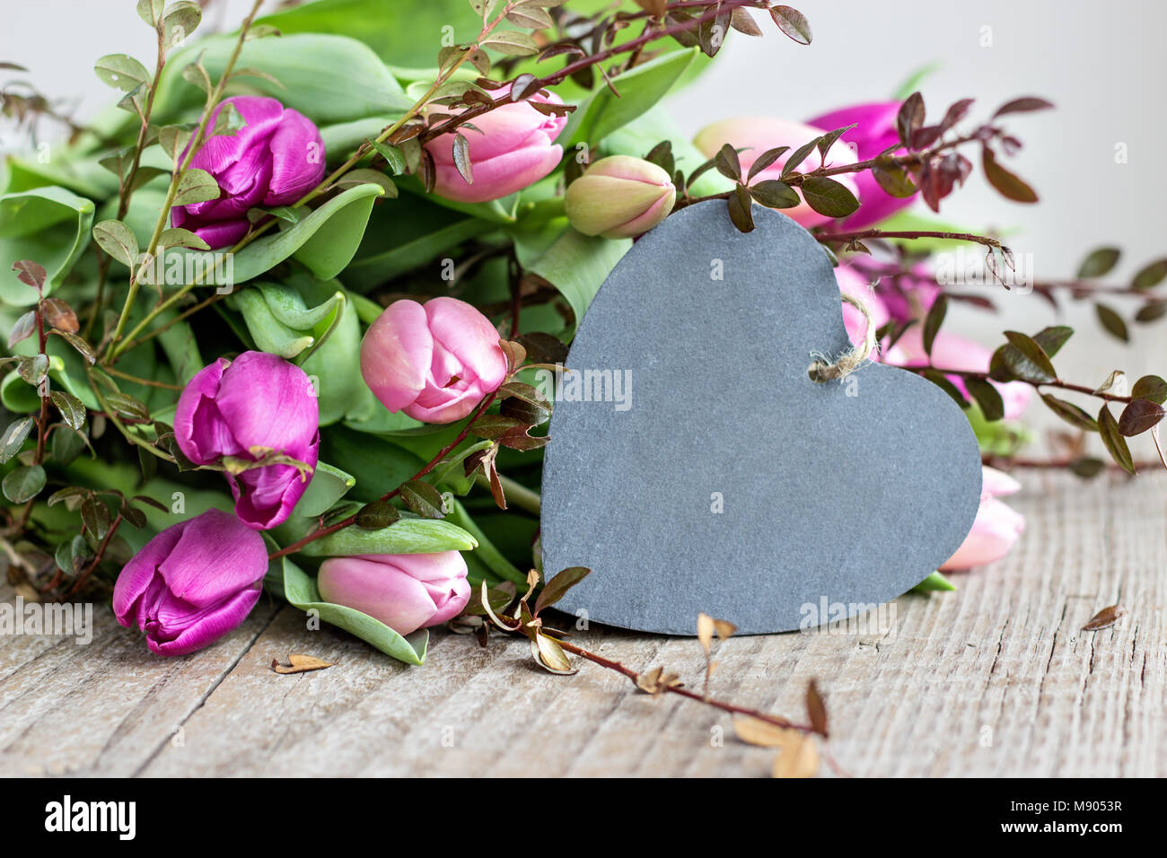 Schönen Blumenstrauß rosa und violett Tulpen mit einem Herzen aus Holz Hintergrund Stockfoto