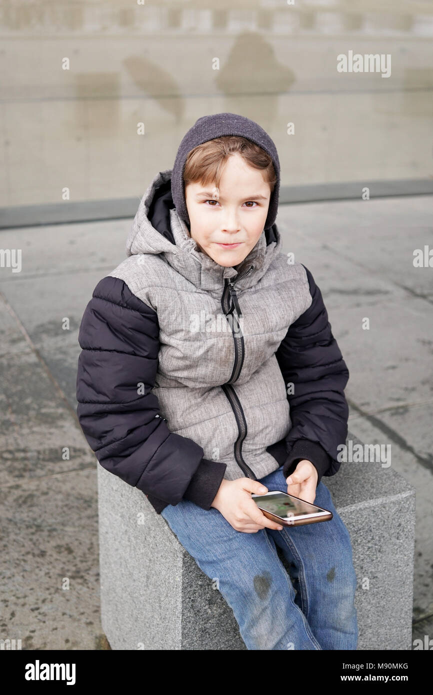 7 Jahre alten Jungen mit Smartphone im Winter Stockfoto