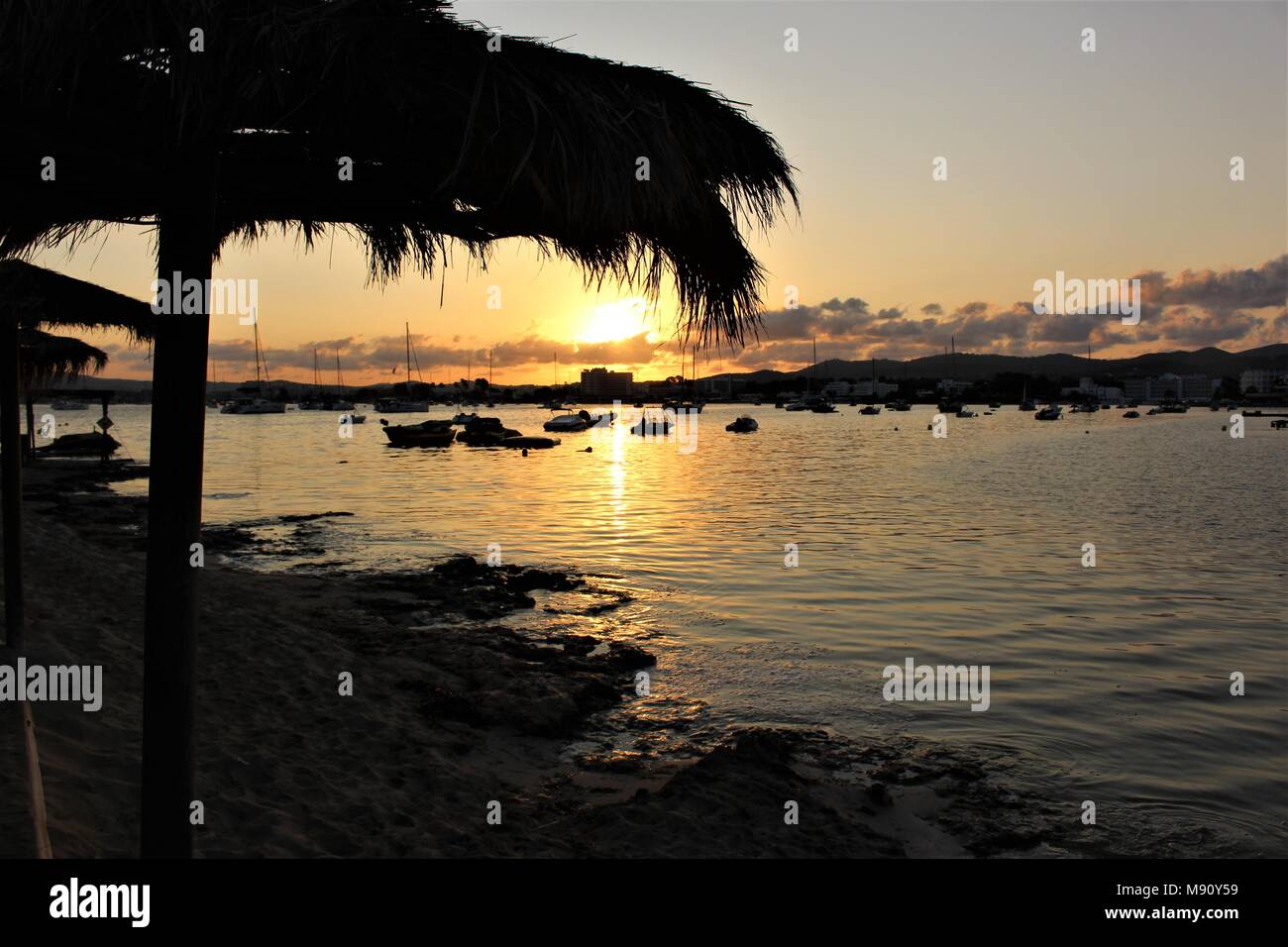 Schönen Sonnenaufgang über Strand und Meer mit Stroh Regenschirm, Ibiza, Spanien Stockfoto