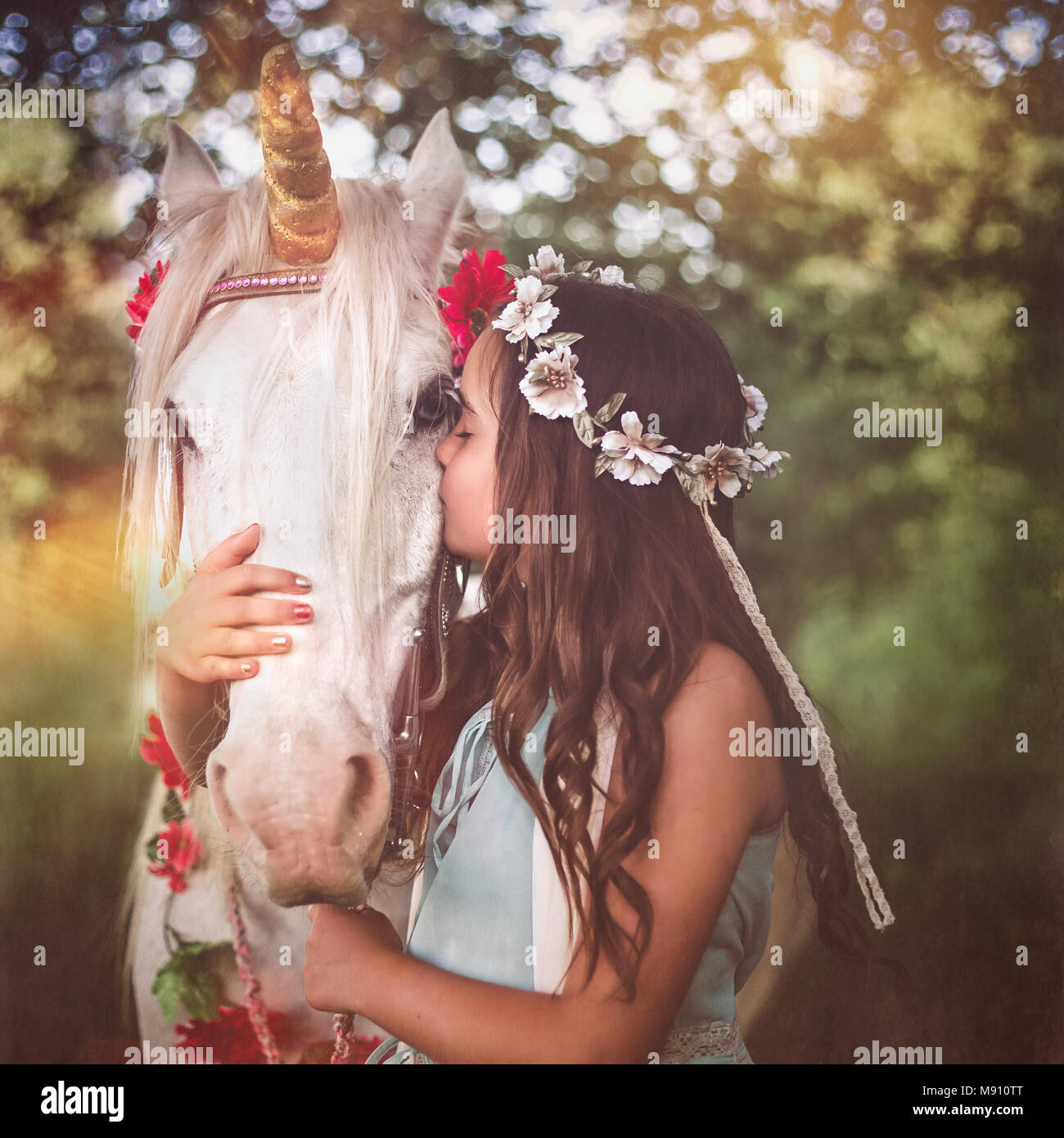 Mädchen mit Blume Haar Kranz Umarmen und Küssen weißes Einhorn. Träume werden wahr Stockfoto